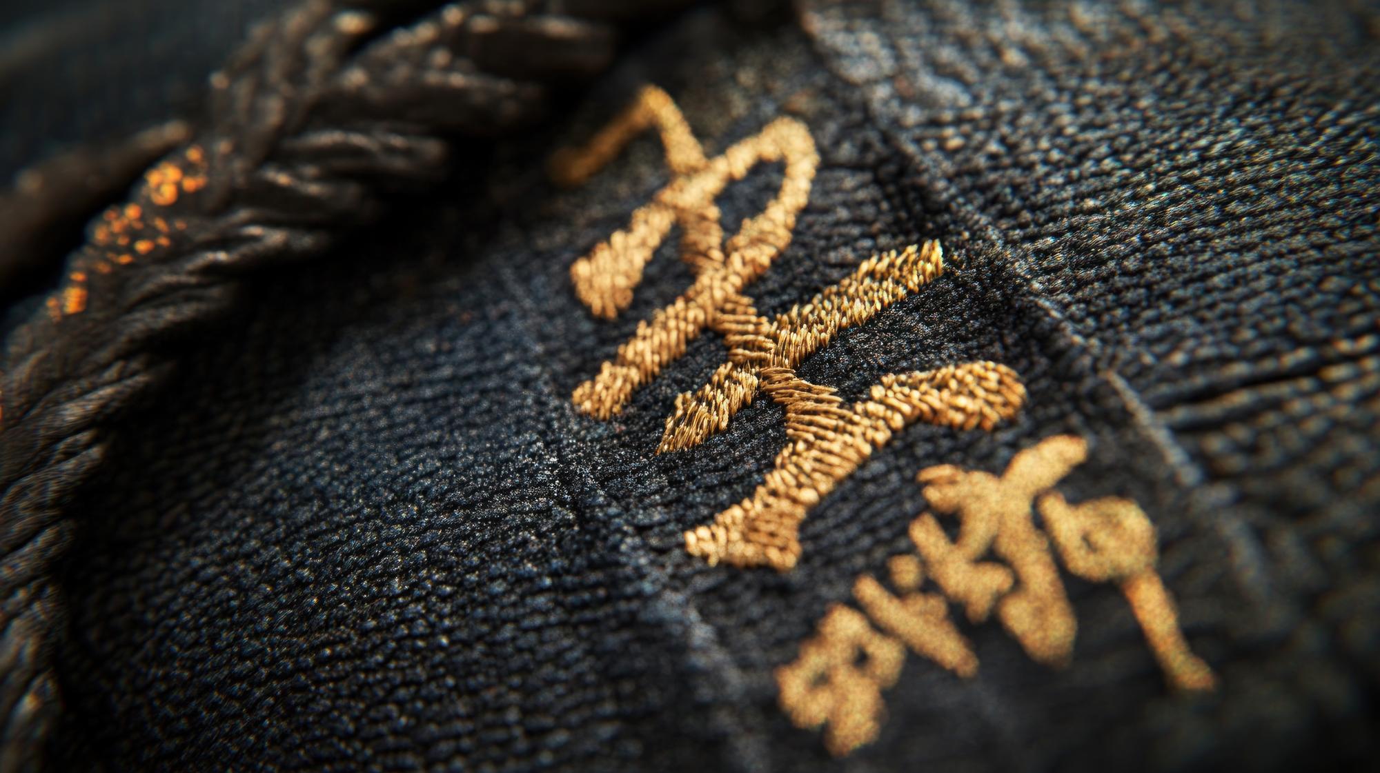 Detail: goldene Stickstiche auf dunklem Stoff